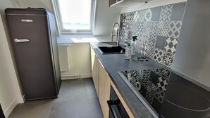 A compact kitchen with a built-in refrigerator, a window above the sink, and patterned backsplash tiles. - Magnificent sea view, direct access to the beach. 4-person apartment (Damgan)