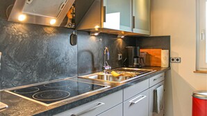 A modern kitchen with a stainless steel sink, a built-in stove, and a coffee maker.