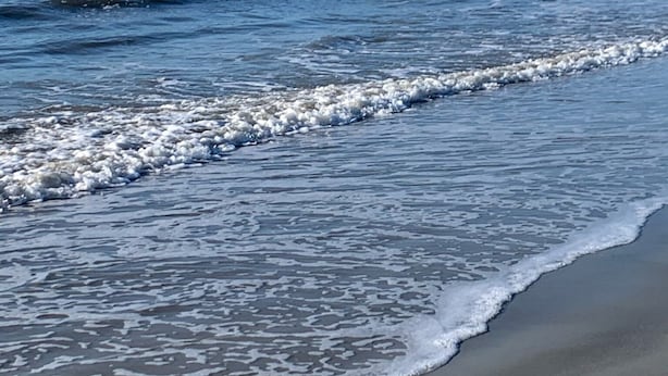 Ein Strand mit sanft anschwellenden Wellen.