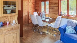 L’intérieur chaleureux d’un chalet comprend un coin repas, un canapé bleu et un meuble en bois doté de portes en verre.