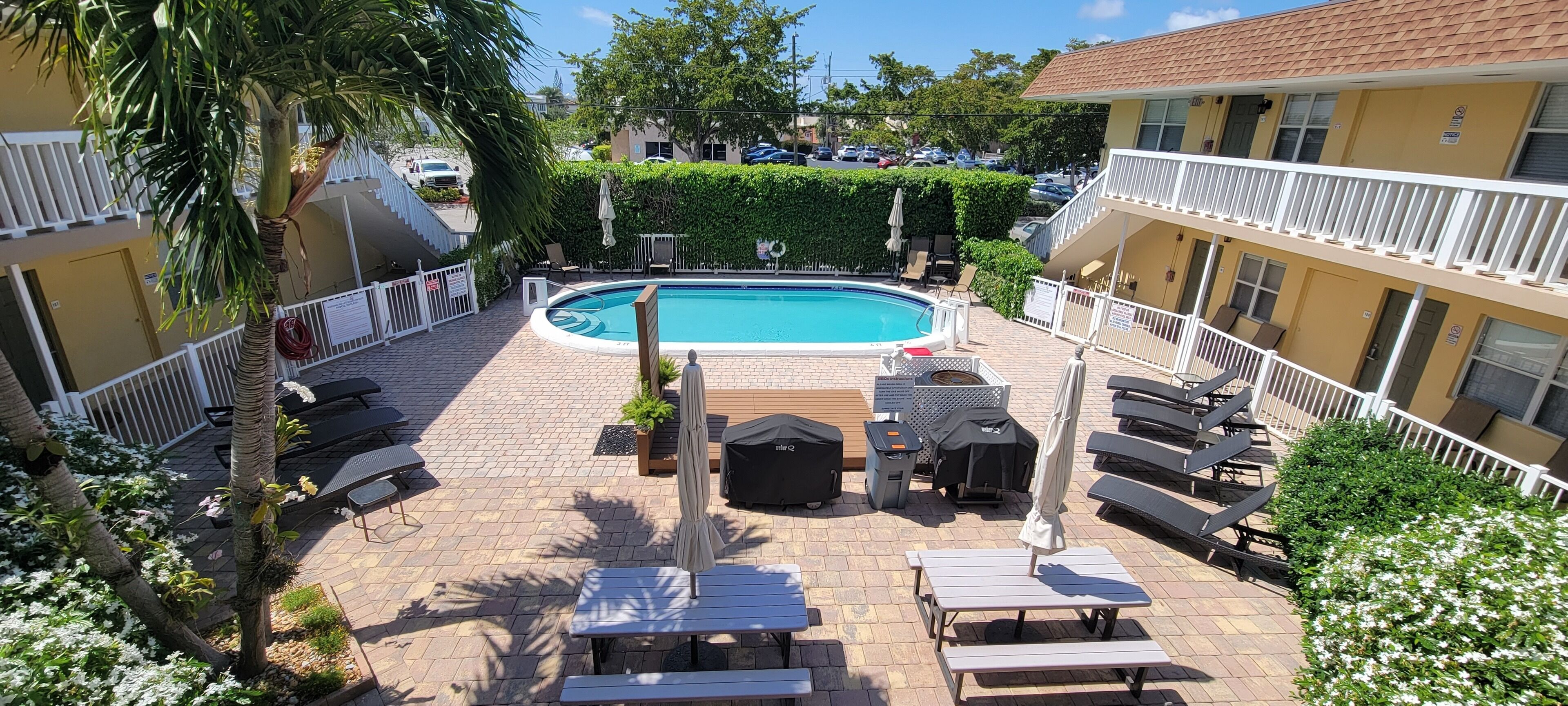 A poolside area with lounge chairs, a pool, and a building with balconies.