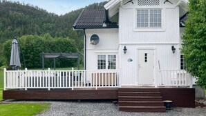 En hvid bygning med veranda, dør og vindue.