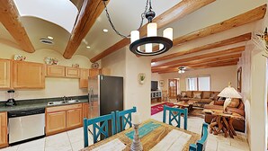 Une cuisine spacieuse avec des meubles en bois, une table à manger et un lustre.