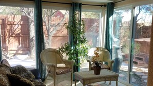 Une pièce baignée de lumière, avec un canapé, deux fauteuils en osier, une table basse et une plante en pot.