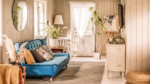 Ein gemütliches Wohnzimmer mit einem blauen Sofa, einer weißen Kommode und einem Bild an der Wand.