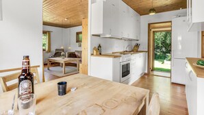 Una cocina moderna con armarios blancos, encimera de madera y un comedor con mesa y sillas.