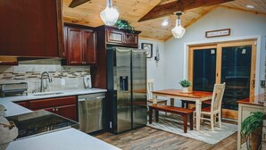 Een keuken met houten kasten, roestvrijstalen apparatuur en een eethoek met een houten tafel en stoelen.