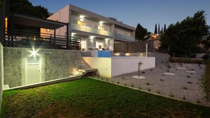 A modern two-story house with a swimming pool, stone walls, and a well-lit outdoor area. - Gorgeous home in Srinjine (Srinjine)