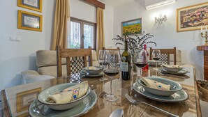 A dining area with a table set for four, featuring a bottle of wine, glasses, and plates. - Lovely home in Casariche (Casariche)