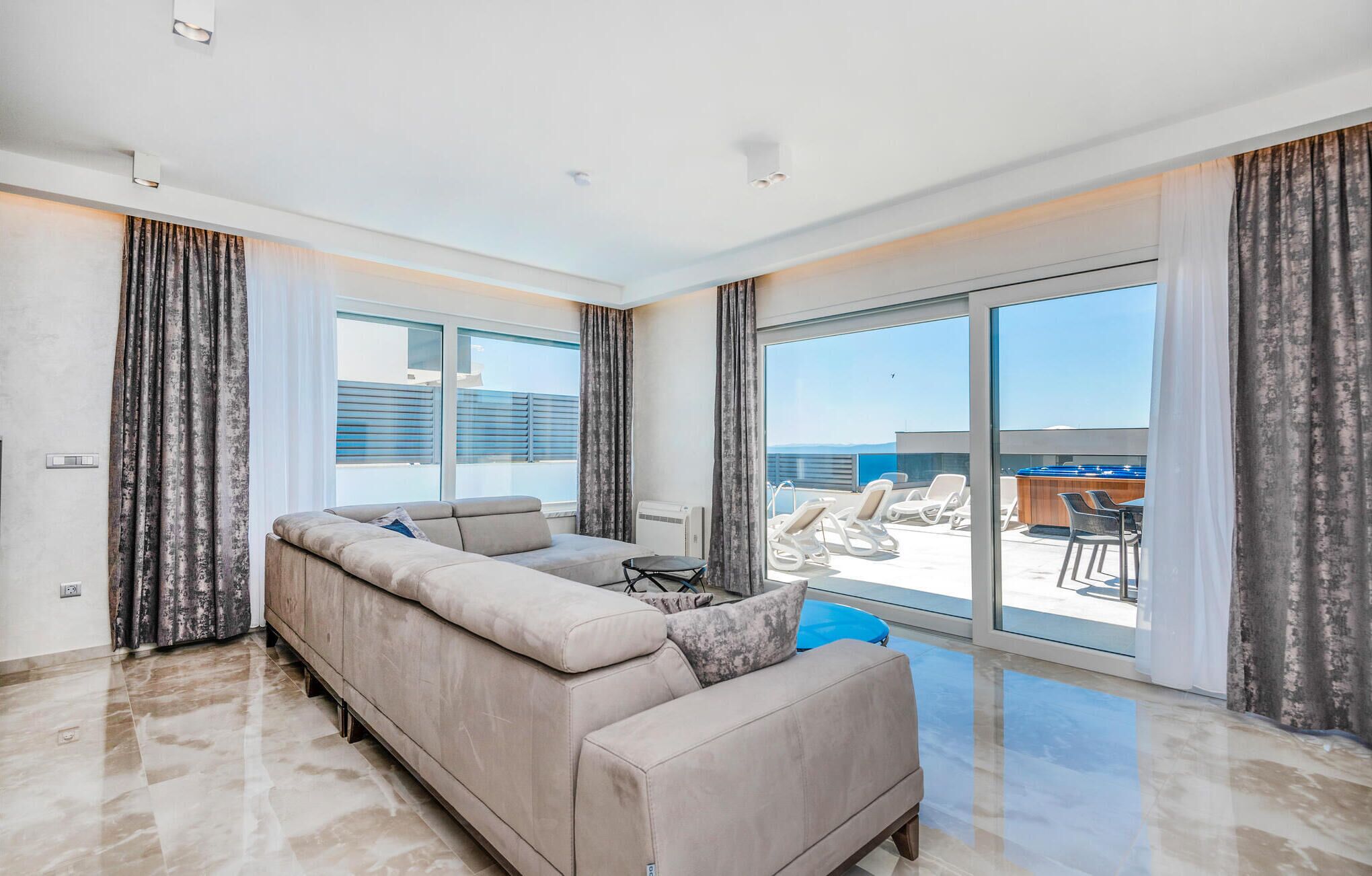 A modern living room with a large sofa, a small table, and a view of the outdoor balcony area.