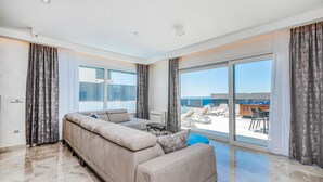 A modern living room with a large sofa, a small table, and a view of the outdoor balcony area. - Lovely home in Makarska (Makarska)