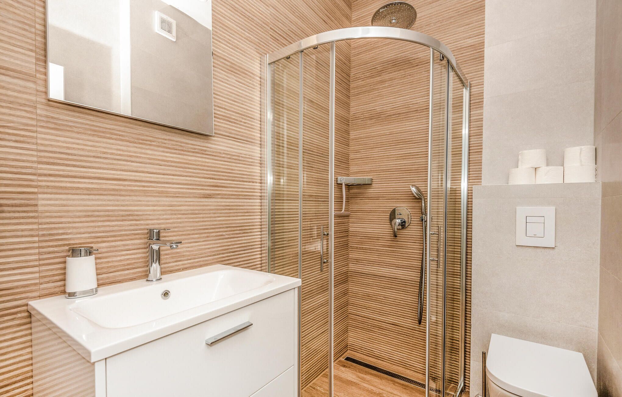 A modern bathroom with a glass-enclosed shower, a white sink, and a toilet.