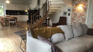 Un salon confortable avec un canapé, une table à manger et des chaises, un coin cuisine et un escalier.