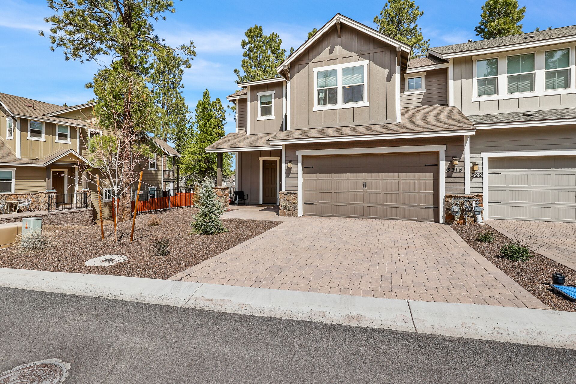A two-story house with a covered front porch, a garage, and a driveway.