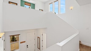 A multi-level interior with a staircase, white walls, and multiple windows. - Mountain Family Getaway w/AC -Sleeps 8! (Flagstaff)