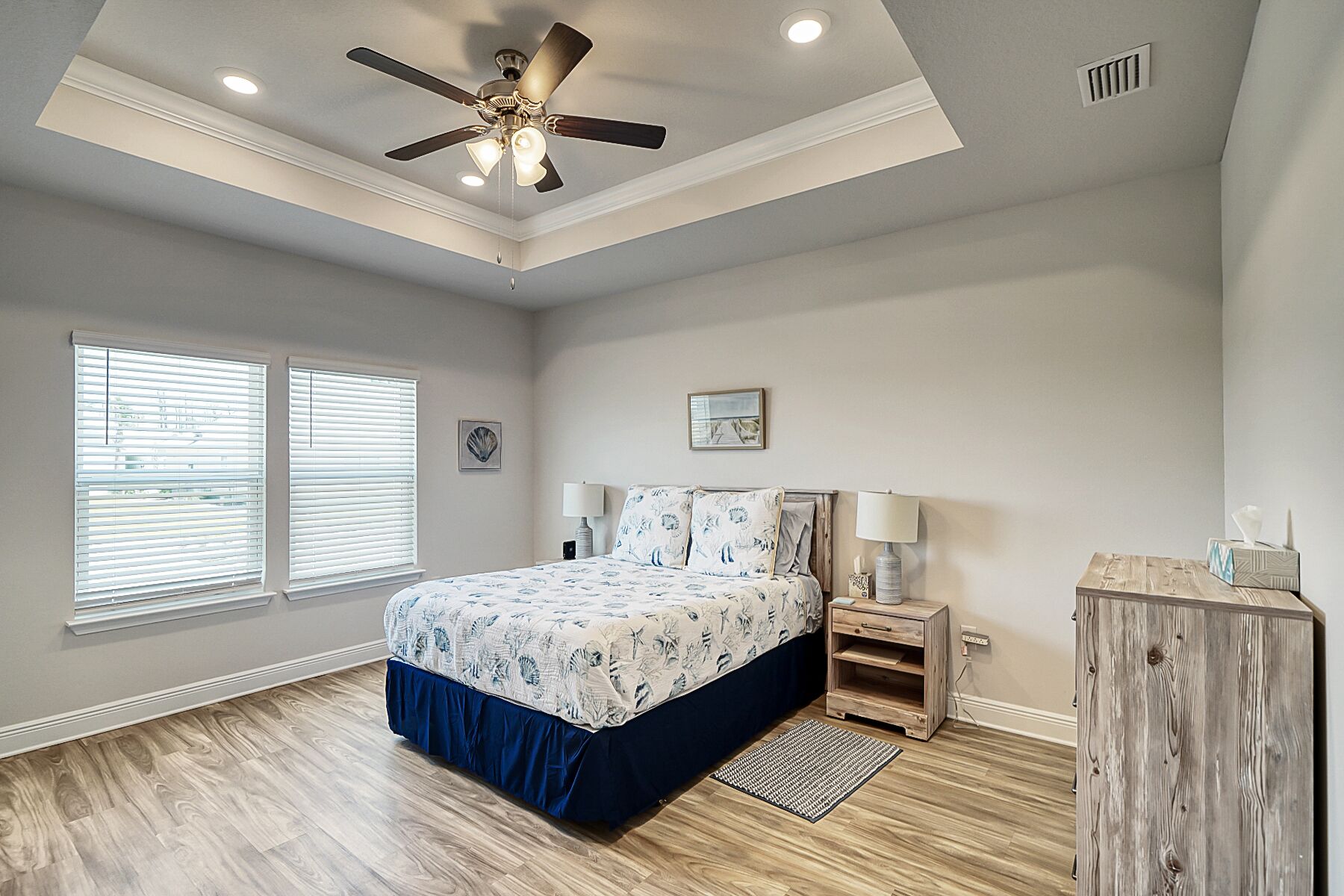 A bedroom with a bed, two bedside lamps, a ceiling fan, and a wooden nightstand.