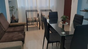 A modern living room with a brown sofa, a glass dining table with black chairs, and a potted plant on the table. - Super cozy apartment / apartment close to the airport (Callao)