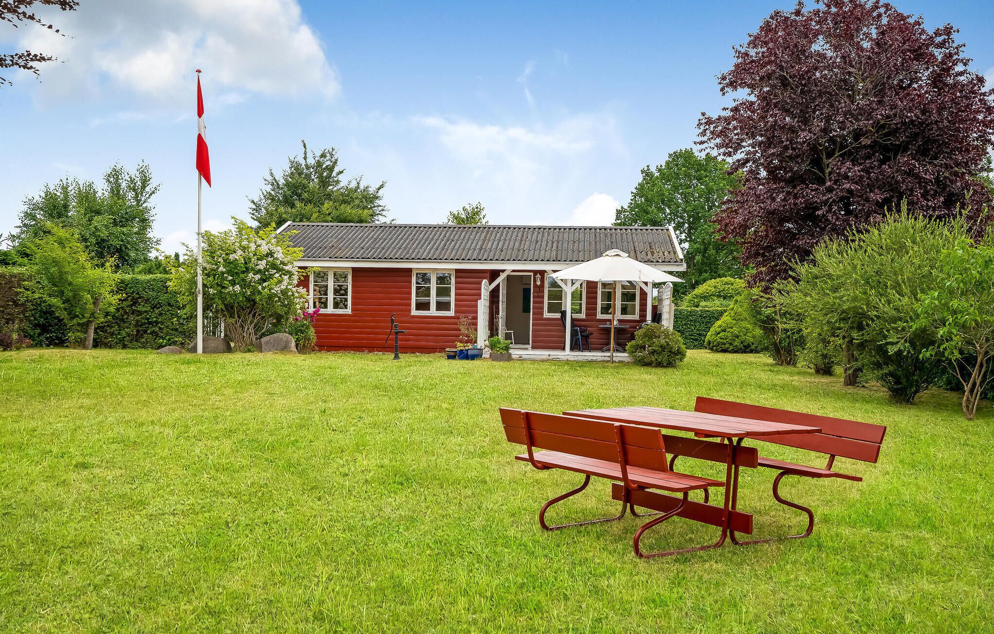 Ein rotes Holzhaus mit Veranda und Fahnenmast.