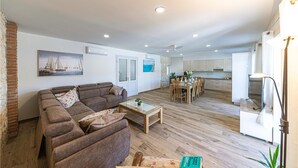 A modern living room with a brown sofa, a glass coffee table, and a dining area with wooden chairs and a white table. - Awesome home in Vinisce (Vinisce)