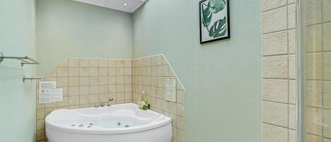 A bathroom with a freestanding bathtub, a glass shower enclosure, and a framed plant on the wall.