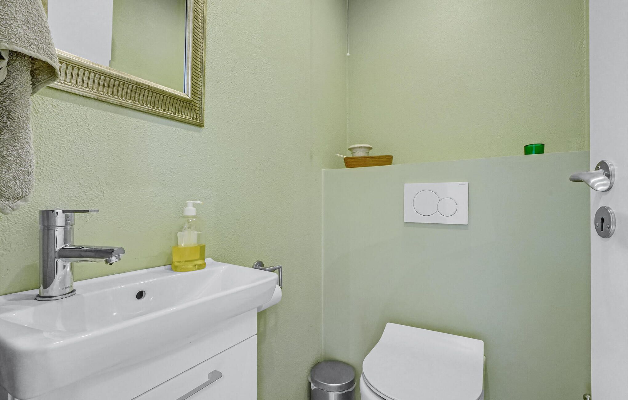 A bathroom with a sink, mirror, toilet, and a towel rack.