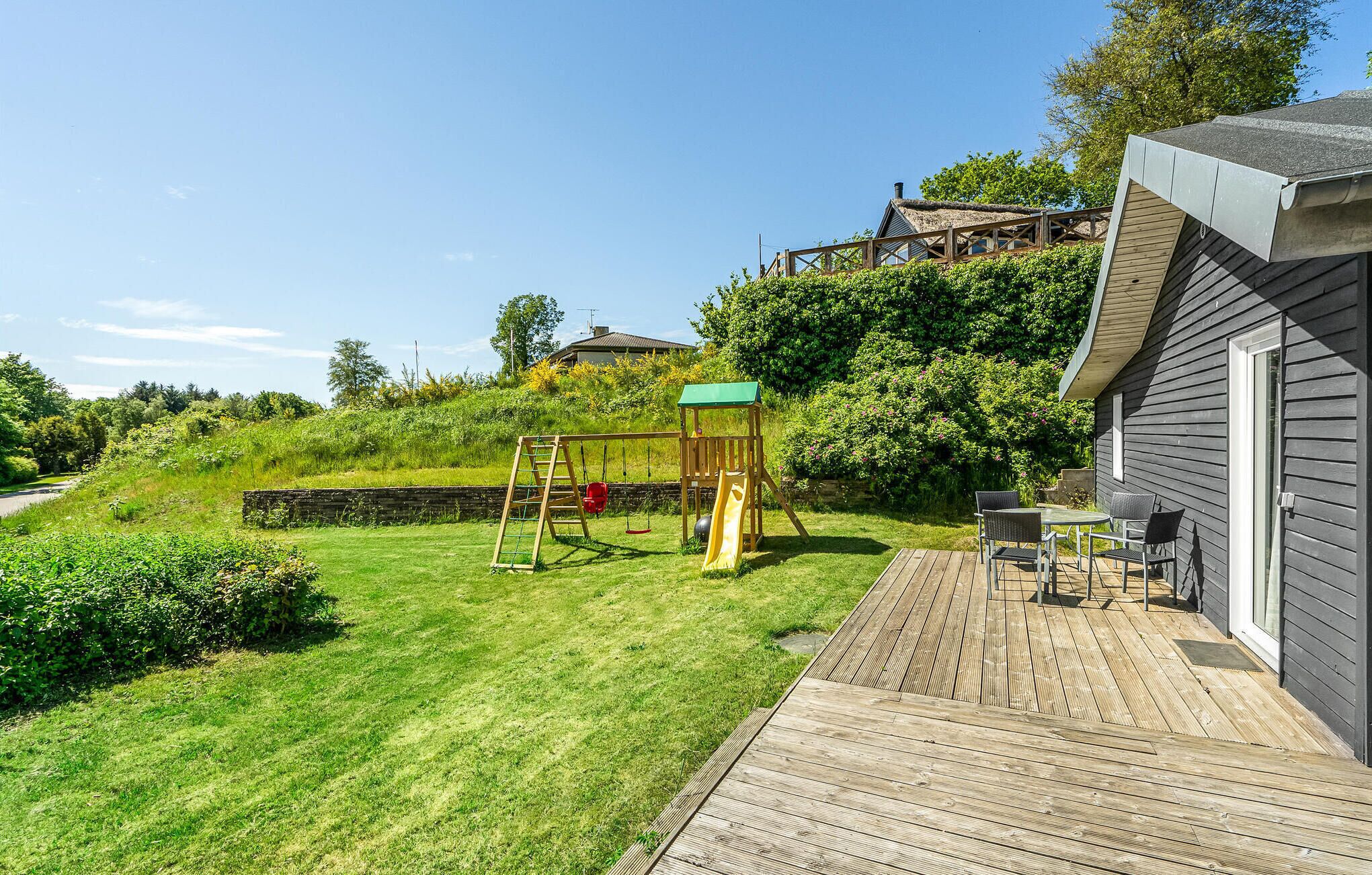 A wooden deck with a swing set and a table with chairs.