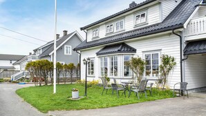 A two-story house with a bay window, a small garden with chairs, and a street view. - 3 bedroom beautiful home in Vanse (Vanse)
