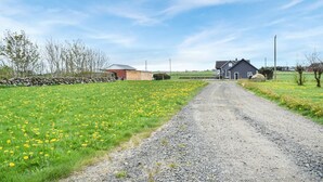 A rural road leading to a farmhouse with a stone wall on one side and a field of yellow flowers on the other. - 3 bedroom beautiful home in Vanse (Vanse)