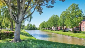 Een rivier die door een park stroomt, met bomen en een rij gebouwen aan de overkant.