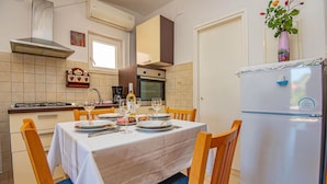 A dining area with a table set for four, a refrigerator, and a kitchen in the background. - Stunning apartment in Brodarica (Brodarica)