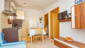 A compact kitchen with a dining area, a TV mounted on the wall, and a fruit bowl on a wooden sideboard. - Stunning apartment in Brodarica (Brodarica)