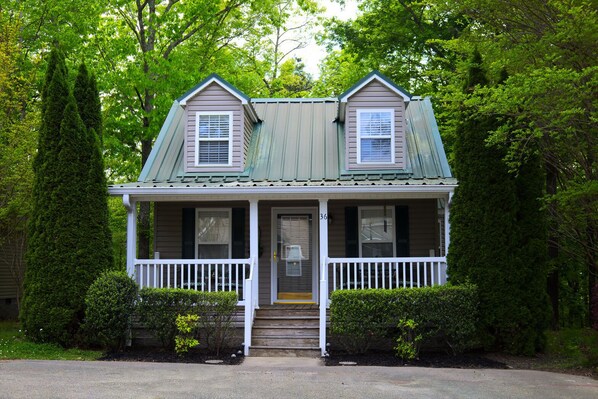 Une maison à deux étages avec un porche, une porte d’entrée et une boîte aux lettres.