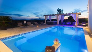 A swimming pool with a pergola and lounge chairs, surrounded by a tiled deck and a view of the mountains. - Gorgeous home in Lovrec with sauna (Lovrec)