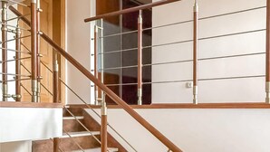 A staircase with a wooden handrail and metal balusters, leading to a landing with a glass door.