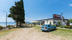 Une route côtière avec une voiture garée devant un bâtiment portant l’inscription « BAR ET RESTAURANT DE QUARTIER ».
