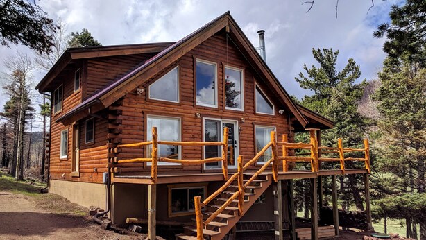 A wooden cabin with a wooden staircase leading to a deck. - Spacious cabin in gated community. (Fort Garland)