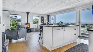 Una cucina moderna con una grande isola, mobili bianchi e vista sull'oceano.