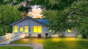 Ein zweistöckiges Haus mit einer Veranda, einem überdachten Bereich und einem kleinen Vorgarten.