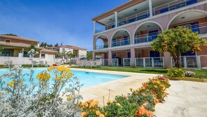 A hotel with a pool, outdoor seating, and a garden with flowers.