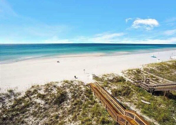 Walk along the beach on a serene shoreline, where a wooden boardwalk leads to the sandy beach.
