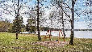 Puistossa on keinuteline, ja taustalla näkyy järvi.
