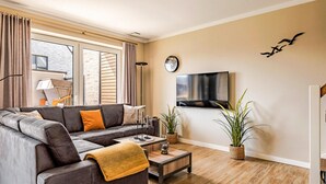 A modern living room with a grey sectional sofa, a coffee table, and two potted plants. - Beach front home in Büsum with sauna (Büsum)