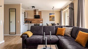 A modern living room with a dark sofa, a coffee table, and a painting on the wall. - Beach front home in Büsum with sauna (Büsum)