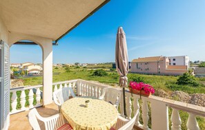 A balcony with a table and chairs, a potted plant, and a view of houses in the distance. - Amazing apartment in Privlaka with WiFi (Privlaka)