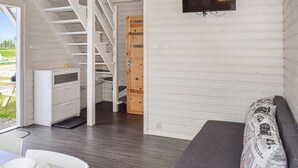 A modern interior with a staircase, a TV mounted on the wall, a sofa, and a dining area with a table and chairs. - Awesome home in Rewal with WiFi (Rewal)