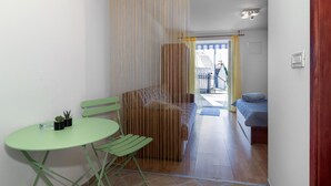 A room with a green table and chairs, a sofa, and a curtain divider. - Amazing apartment in Jadranovo with WiFi (Jadranovo)
