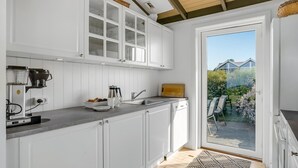 A modern kitchen with white cabinets, a coffee machine, and a view of the garden through the door. - Amazing home in Slagelse with WiFi (Slagelse)
