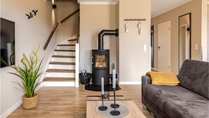 Uma sala de estar com lareira moderna, escada, sofá e planta em vaso.