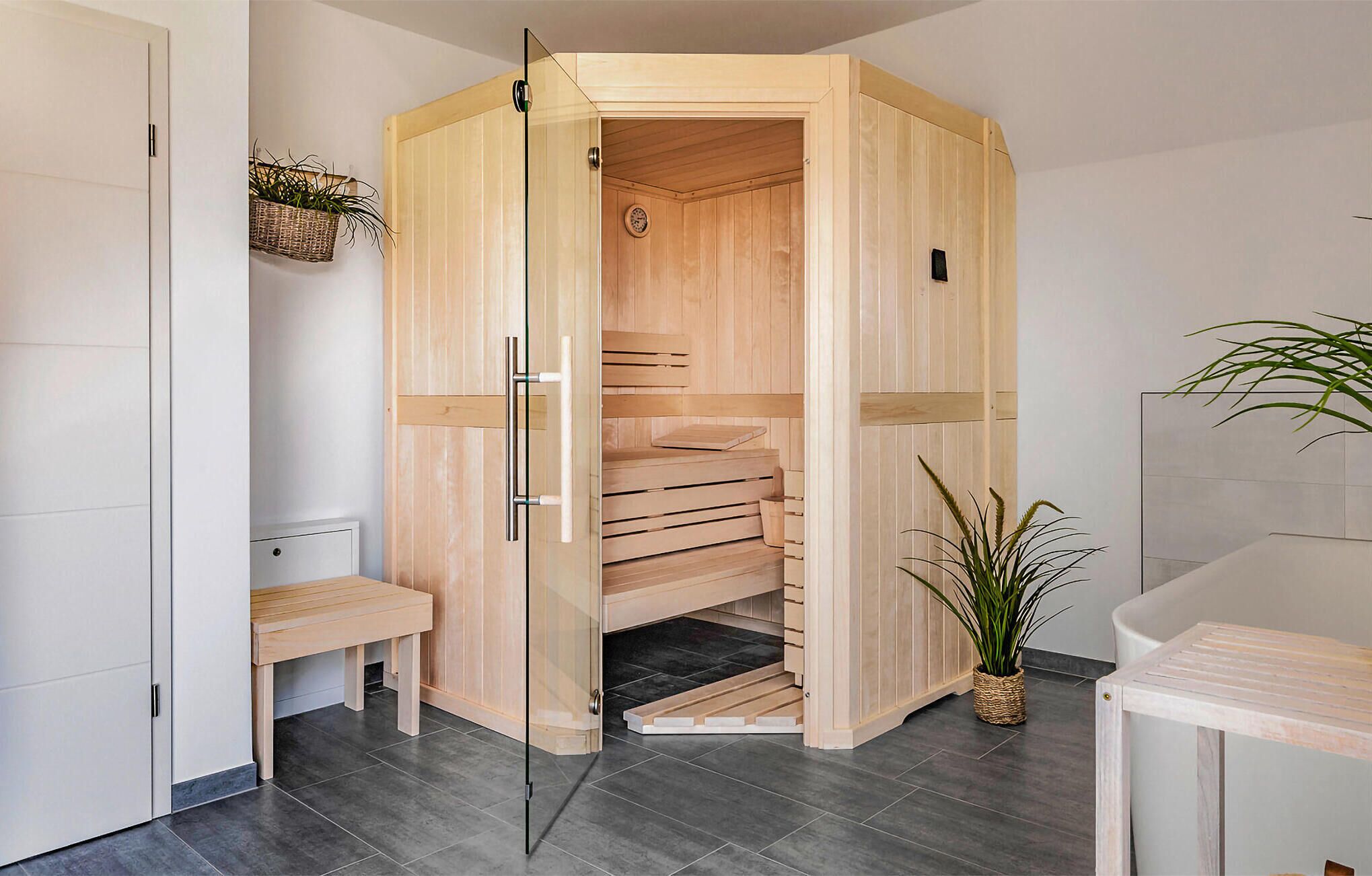 Un sauna avec un banc en bois, un siège et une petite table.