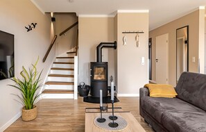 A living room with a modern fireplace, a staircase, a sofa, and a potted plant.